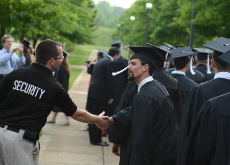 Adam Panisiak, shift supervisor for safety and security, congratulates Mark Waite, Christian studies graduate, during the processional for Spring Graduation.  - Photo by Jacob Moore