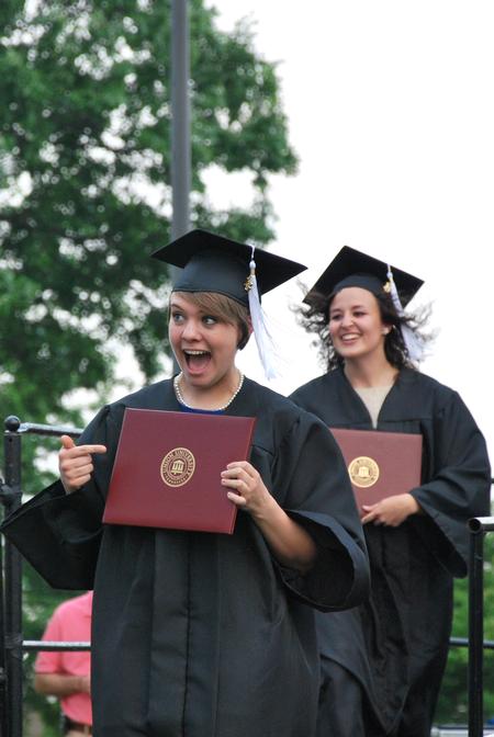 Krista Bradley, teaching English as a second language graduate, and Amanda Browning, family studies graduate, celebrate as they walk back to their seats after receiving their diplomas at Spring Graduation. - Photo by Anne Richoux
