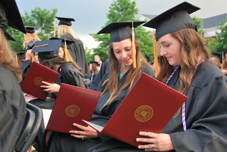 Graduates excitedly open and look at their diplomas during Spring Graduation. - Photo by Anne Richoux