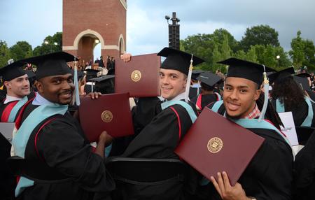 Deonte Singfield, Joshua Shelley and Preston Scott, master of urban education graduates, hold up their newly received diplomas at Spring Graduation. - Photo by Jacob Moore