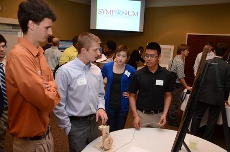 At center left, Cody Giles, senior engineering major, talks about his group's experimentation using an oscillating steam engine with engineering students Shane Caver (left), Lydia DeWolf and Andrew Tan. - Photo by Jacob Moore