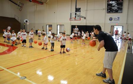 Trevor Lydic, assistant men's basketball coach, coaches children on dribbling during the athletic department's basketball Pee Wee Camp in the Fred DeLay Gymnasium. - Photo by Jacob Moore