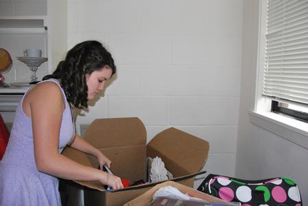 Mary Scarlett Greenway, freshman pre-physical therapy major, unpacks boxes in her room during new student move-in day.  - Photo by Anne Richoux