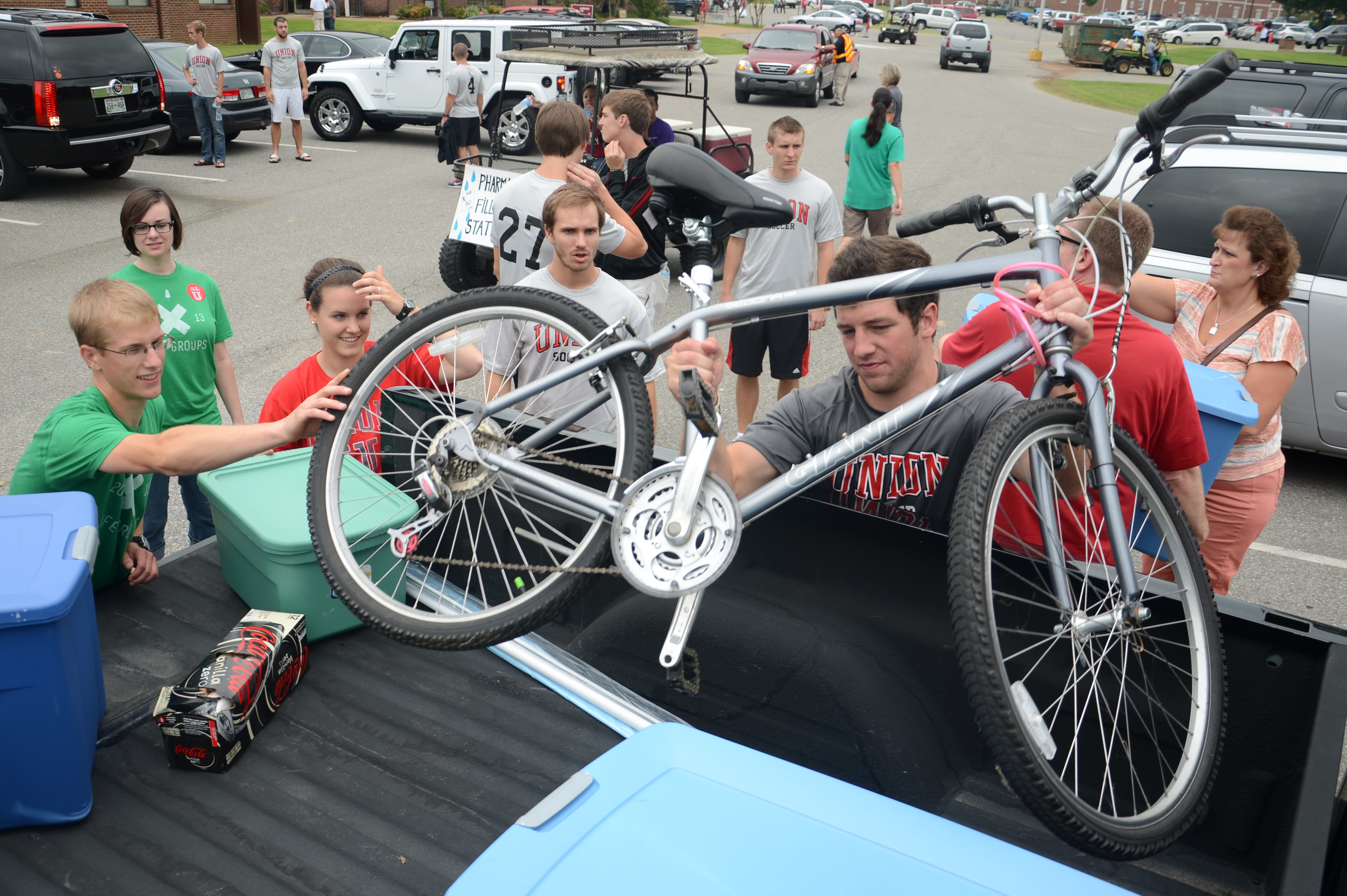JR Landham, assistant men's soccer coach, helps move a bike to a new student's room during move-in day. - Photo by Jacob Moore