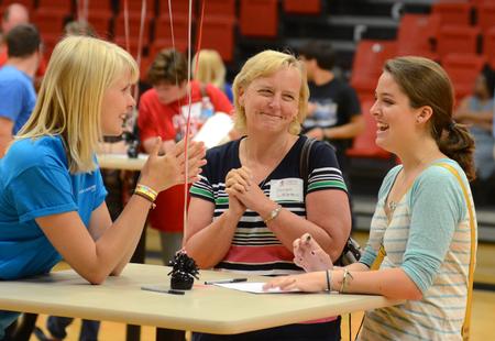 At left, Linnea Verhagen, sophomore nursing major and resident advisor, checks in with parent Karen Littleton and Emily Littleton, freshman international business major, during new student move-in day. - Photo by Jacob Moore
