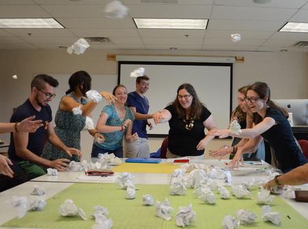 At center, Melinda Posey, assistant professor of art, leads graphic design students in a 'snowball fight' during class in Jennings Hall. In small groups, students then sorted into categories the items written on the pieces of recycled paper. Their categories were compared with the categories of other groups. The exercise was a visual example of how humans receive and organize ideas in both similar and different ways. - Photo by Jacob Moore