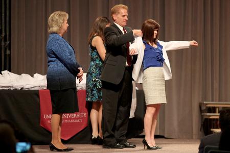 Alex Blanton receives her white coat from George DeMaagd, associate dean of academic administration, during the annual white coat ceremony for new pharmacy students.  - Photo by Kristi McMurry Woody