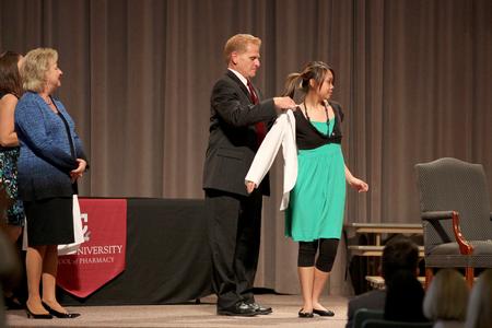 Ann Tach receives her white coat from George DeMaagd, associate dean of academic administration, during the annual white coat ceremony for new pharmacy students.  - Photo by Kristi McMurry Woody