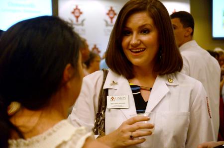 Brittany Reeves, doctor of pharmacy class of 2016, encourages students who received their own white coats at the sixth annual white coat ceremony. - Photo by Amanda Rohde