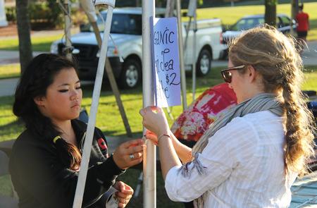 Erin Crocker, freshman Christian ministry and missions major, and Sarah Bostic, junior nursing major, hang up a sign for the International Justice Mission booth at Union Night during Family Weekend. - Photo by Matt McDaniel