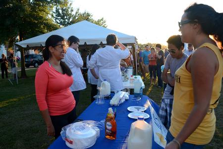 Gabi Simas, junior chemistry major, talks with James Vo, junior information technology major, and Rachel Robbins, senior music and psychology double major, at the SMACS booth during Union Night on the Great Lawn.  - Photo by Anne Richoux