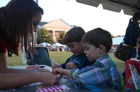 Student Teacher Education Association (STEA) graduate assistant Miranda Jackson helps children with crafts at the STEA booth during Union Night on the Great Lawn.  - Photo by Anne Richoux
