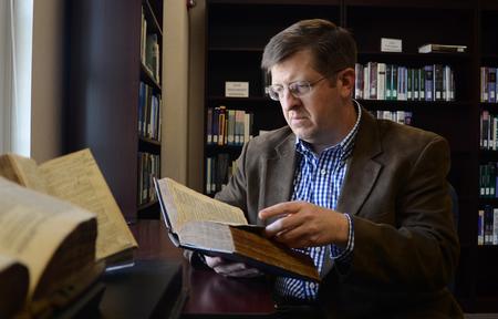 Ray Van Neste looks through a 1613 edition of the King James Bible that was recently donated to the R.C. Ryan Center for Biblical Studies. - Photo by Jacob Moore