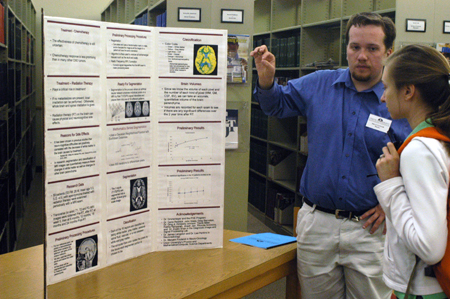 Brian Taylor, math major, explains his symposium poster project to senior Catherine Lee, nursing major, in the library. Taylor will work with St. Jude this summer. - Photo by Lindsay Stavish