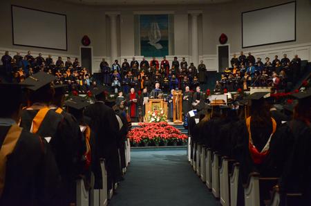 Chris Mathews, chair of the music department, leads in singing the Alma Mater at the conclusion of Fall Commencement Services. - Photo by Amanda Rohde