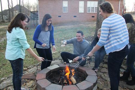 Jonathan Abernathy, director of disability services, roasts marshmallows with the students during the Be our Guest dinner at Blake Pennington's house. - Photo by Matt McDaniel