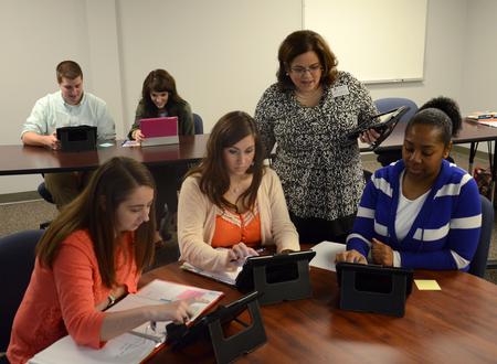 Nancy Cherry, director of the M.A.Ed. program, checks in on graduate students looking at online teaching resources during classtime. - Photo by Jacob Moore