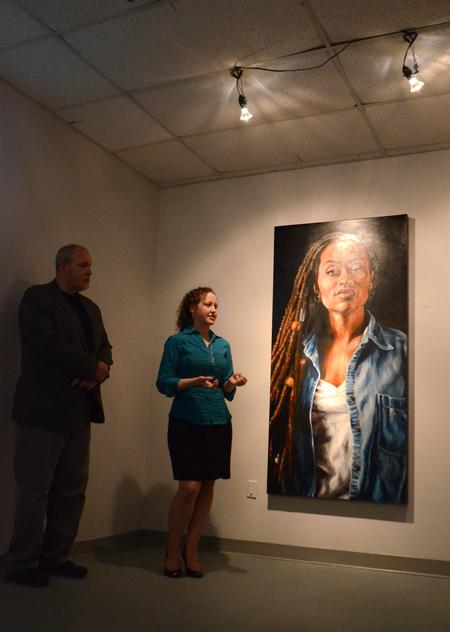 Betsy Marsch, senior art major, talks about her portrait paintings during her senior show while Christopher Nadaskay, university professor of art, listens. - Photo by Amanda Rohde
