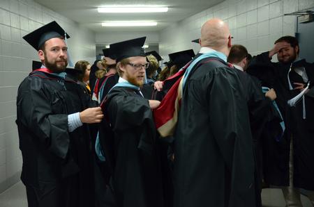 Graduates receiving their M.Ed. assist each other as they wait to walk in to Spring Commencement Services held at the Omen Arena. - Photo by MiKalla Cotton