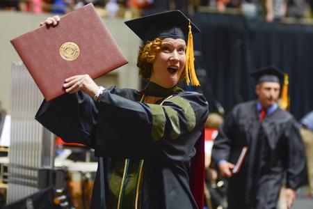 Donna Randolph, doctor of Pharmacy, cheers with her degree in hand for her friends and family watching in the crowd at Spring Commencement in the Oman Arena. - Photo by Meg Rushing