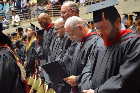 Master of Christian Studies graduates bow their heads in prayer during the Spring Commencement Services. - Photo by Emily Stookey
