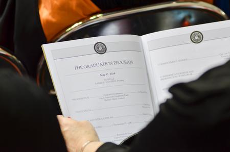 A member of the audience reads the program for Spring Commencement Services. - Photo by Emily Stookey