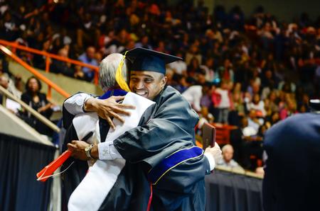 William Murray, engineering graduate from Chaguanas, Trinidad, embraces David S. Dockery after blowing his horn in celebration on stage after being awarded his degree during Spring Commencement. - Photo by Kathleen Murray