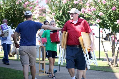 Hunter Baker, associate professor of political science, helps new students carry belongings to their rooms during move-in day. - Photo by Kristi McMurry Woody