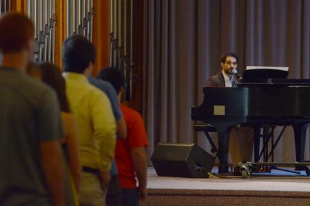 Cody Curtis, assistant resident director for the male quads, plays piano and leads the congregation in a song at the beginning of chapel. - Photo by Emily Stookey