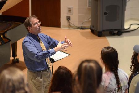 Director of the Women's Choir, David Dennis, professor of music, rehearses with his students for an upcoming event. - Photo by Emily Stookey