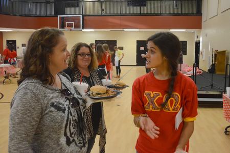 Katy Wade, senior zoology major, guides guests to their seats at the Chi Omega BBQ fundraiser for the Make-A-Wish foundation during Family Weekend. - Photo by Emily Stookey