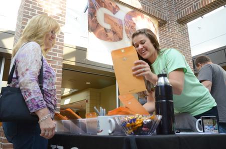Brittany Winfree, resident life secretary, gives Family Weekend registrants their info upon arrival. - Photo by Amanda Rohde