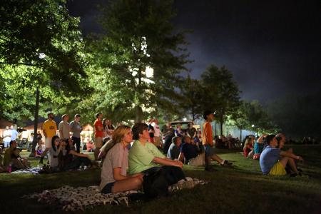 Students and their families relax on the grass as the Family Weekend fireworks display goes off to conclude Union Night.  - Photo by Kristi McMurry Woody