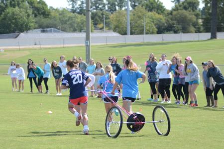 Members of the sorority Zeta Tau Alpha begin the chariot race as their sisters cheer them on during Greek Olympics. - Photo by Emily Stookey