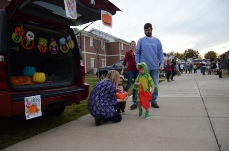 Benjamin Bredow, residence director, and his wife and children get some  candy during Trunk or Treat hosted by the Student Government Association's sophomore council. - Photo by MiKalla Cotton