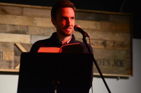 Jason Crawford, assistant professor of English, reads at the English Department's A Christmas Carol reading and cookie exchange event in Barefoots Joe. - Photo by MiKalla Cotton