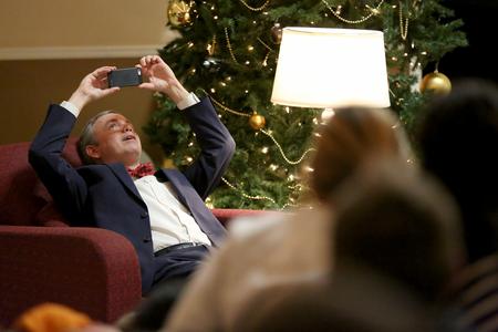 Dub Oliver, president of the university, leans back to take a photo of the students gathered in the McAfee Commons for Christmas with the Olivers. - Photo by Kristi McMurry Woody