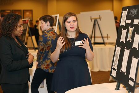 Emily Malone, senior art major, explains her poster and work during the annual Scholarship Symposium.  - Photo by Kristi McMurry Woody