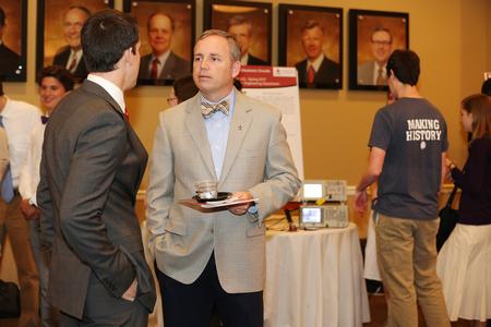 Dub Oliver, president of the university, chats with a student about his research at the Scholarship Symposium poster presentations. - Photo by Kristi McMurry Woody