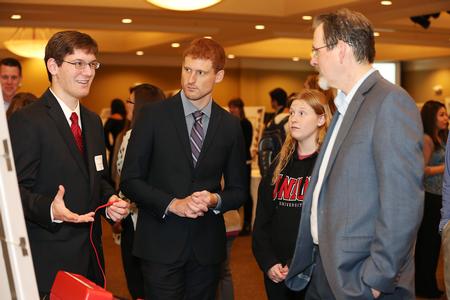 Aaron Hively (left), junior engineering major, discusses his project at the Scholarship Symposium poster sessions. - Photo by Kristi McMurry Woody