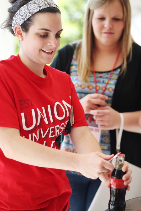 Mallory Lamm, sophomore social work major, helps a new student pop the top off her Coke during a Summer Orientation refreshment break. - Photo by Kristi McMurry Woody