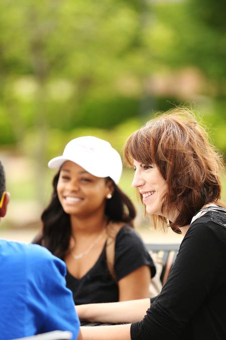 Chris Bailey, assistant professor of English and director of composition support, talks with a group of students on the Barefoots Joe patio. - Photo by Kristi McMurry Woody