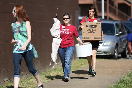 Kim Lindsey-Goodrich, associate professor of pharmacy practice, and Sarah Belcher, graphic design specialist, help a new student carry her things during Move-in Day. - Photo by Kristi McMurry Woody