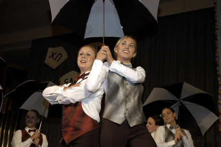 Freshman Kate Rawls and sophomore Rachel Winford creatively used umbrellas in their large group routine for Chi Omega during All-Sing 2004. - Photo by Kathleen Murray