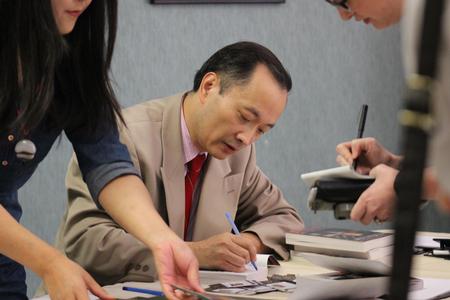 Ming Wang, director of Wang Vision 3D Cataract and LASIK Center, signs his books for students, the funds of which will go to help patients have free eye treatment.  - Photo by Sol Bee Park