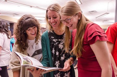 Kaylee Gibson, junior public relations major, Kaylene Portell, senior social work major, and Ruthie Johnson, senior Christian studies major, admire the newly-released edition of the Cardinal & Cream magazine. - Photo by David Parks