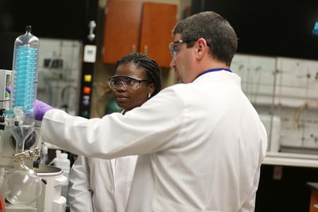 Blake Watkins, chair of pharmaceutical sciences, helps a student set up an experiment in the lab. - Photo by Kristi McMurry Woody