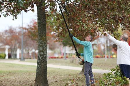 Dub Oliver, president of the university, and Dan Griffin, vice president for enrollment management, trim the trees along the Great Lawn during Campus & Community Day. - Photo by Kristi McMurry Woody