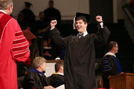 Peyton Penuel, digital media studies graduate, celebrates as he walks to get his diploma during fall commencement services. - Photo by Kristi McMurry Woody