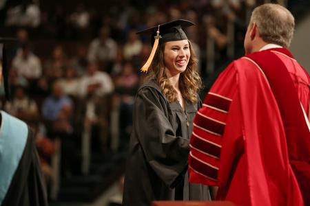 Haley Dauer, nursing graduate, accepts her diploma from Dub Oliver, president of the university, during fall commencement services.  - Photo by Kristi McMurry Woody